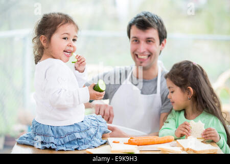 Heureux père de préparer des sandwiches pendant que filles manger à la maison Banque D'Images