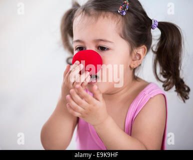 Cute girl portant des nez de clown à la maison Banque D'Images