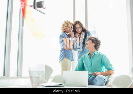 Smiling businessman looking at collègues femmes commérer dans creative office Banque D'Images