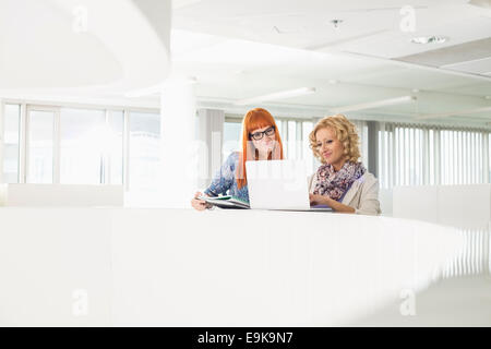 Les femmes d'affaires créatifs using laptop together in office Banque D'Images