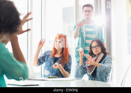 Angry woman throwing paper balls sur collègue in creative office Banque D'Images