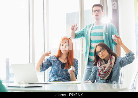 Angry woman throwing paper balls in creative office Banque D'Images