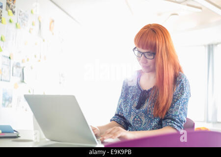 Businesswoman using laptop in creative office Banque D'Images