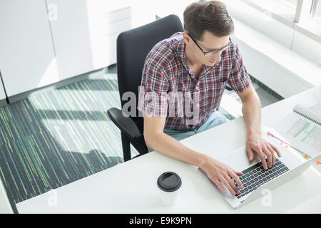 High angle view of businessman using laptop at desk in creative office Banque D'Images