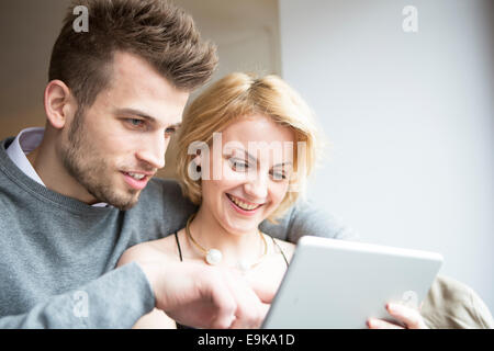 Happy young couple using digital tablet in cafe Banque D'Images