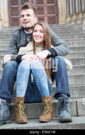 Toute la longueur du jeune couple sitting on steps outdoors Banque D'Images