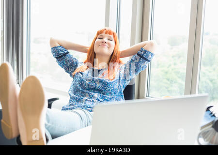 Businesswoman relaxing with feet up in creative office Banque D'Images