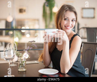 Portrait of happy young woman having coffee at restaurant Banque D'Images