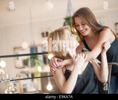 Happy woman embracing amie in cafe Banque D'Images