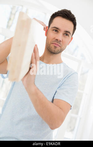 Mid-adult man carrying planche en bois sur l'épaule Banque D'Images