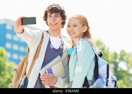 Amis de l'université en tenant avec selfies smart phone at campus Banque D'Images