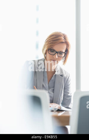 Jeune businesswoman writing at desk in office Banque D'Images