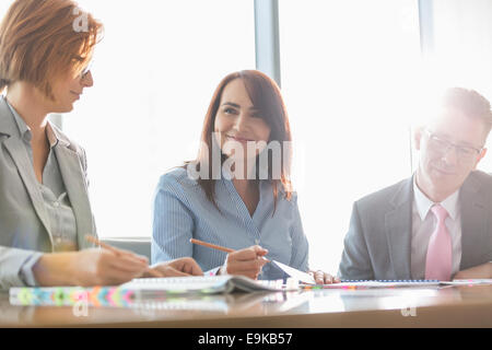 Smiling businesswoman avec des collègues dans la salle de réunion Banque D'Images