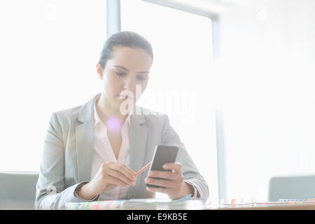 Young businesswoman using cell phone in office Banque D'Images