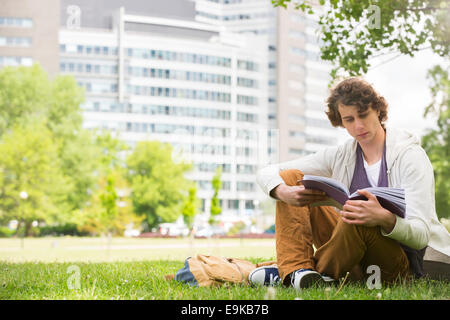 Toute la longueur du jeune homme lecture livre sur college Campus Banque D'Images