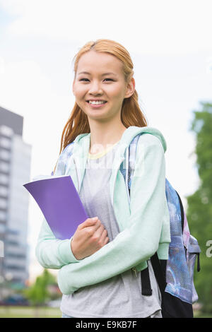 Portrait of happy young woman holding book at college Campus Banque D'Images