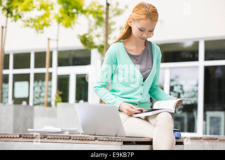 Young woman reading book at college Campus Banque D'Images