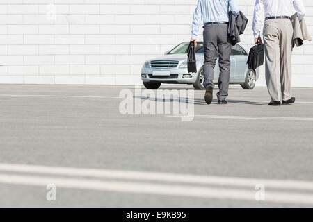 La section basse des hommes exerçant son porte-documents en marchant vers la voiture sur street Banque D'Images