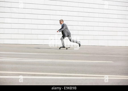 Vue latérale du businessman skateboarding on street Banque D'Images