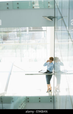 Businesswoman using cell phone in office Banque D'Images