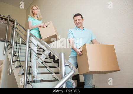 Couple carrying cardboard boxes tout en se déplaçant vers le bas à de nouvelles étapes accueil Banque D'Images