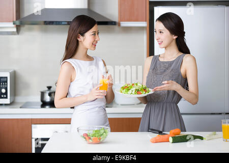 Jeune femme cuisiner et parler avec son ami dans la cuisine Banque D'Images