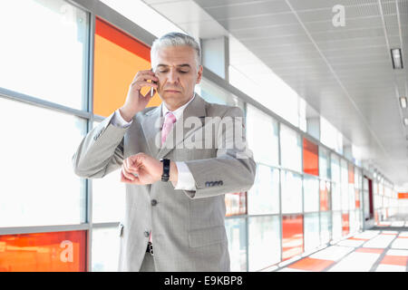 Middle aged businessman contrôle de temps en attendant l'appel à la station de chemin de fer Banque D'Images