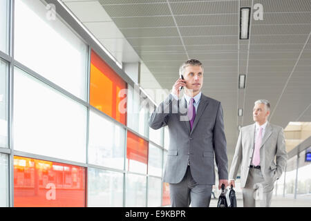 Middle aged businessman on call en marchant dans railroad station Banque D'Images