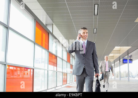 Middle aged businessman on call en marchant dans railroad station Banque D'Images