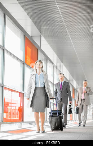 Toute la longueur de businesspeople with luggage walking in railroad station Banque D'Images