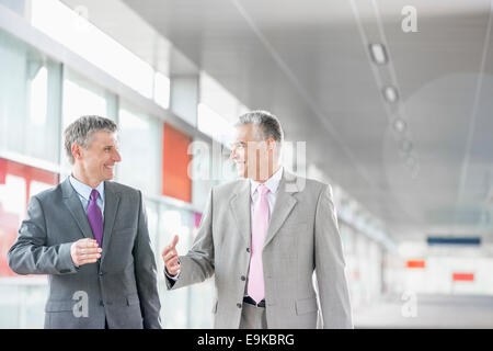 Heureux les hommes d'âge moyen de parler tout en marchant dans railroad station Banque D'Images