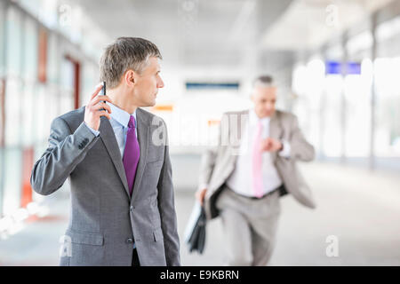 Middle aged businessman looking at collègue fonctionnant en railroad station Banque D'Images