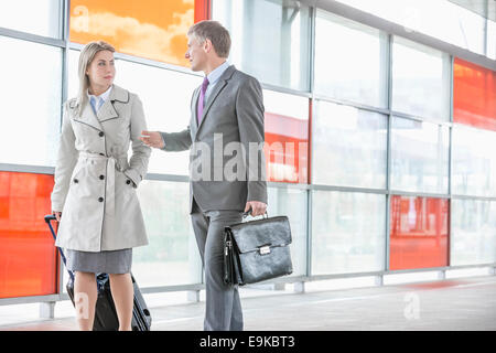 Businessman and businesswoman talking en marchant sur la plate-forme ferroviaire Banque D'Images