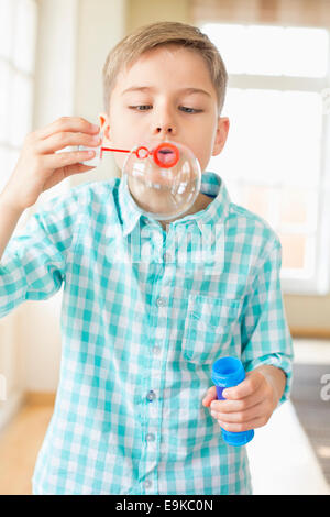 Cute boy playing with bubble wand à la maison Banque D'Images