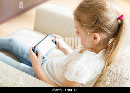 Vue arrière du fille jouant un jeu vidéo à la maison Banque D'Images