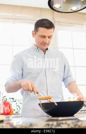 Middle-aged man cooking in kitchen Banque D'Images