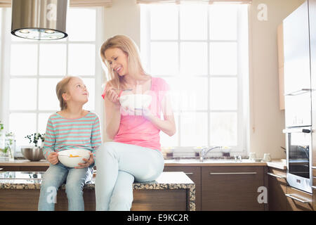 Happy mother and daughter having breakfast in kitchen Banque D'Images