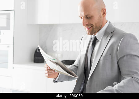 Young Woman Reading newspaper in kitchen Banque D'Images