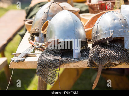 Armure médiévale, casques et d'épées se coucher sur une table en bois à l'extérieur. Banque D'Images