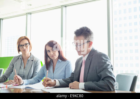 Les gens d'affaires écrit sur books at conference table Banque D'Images