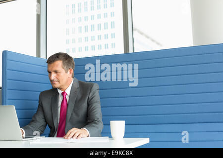 Mature businessman using laptop at desk Banque D'Images