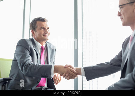 Mature businessmen shaking hands in office Banque D'Images