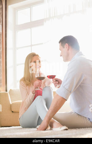 Heureux couple tout en ayant le vin rouge à la maison Banque D'Images