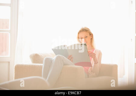 Beautiful woman reading magazine à la maison Banque D'Images