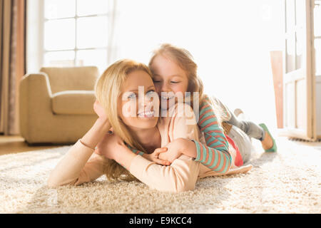 Portrait of happy mother with daughter lying on floor at home Banque D'Images