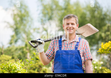 Portrait of happy man carrying bêche sur l'épaule dans les pépinières Banque D'Images