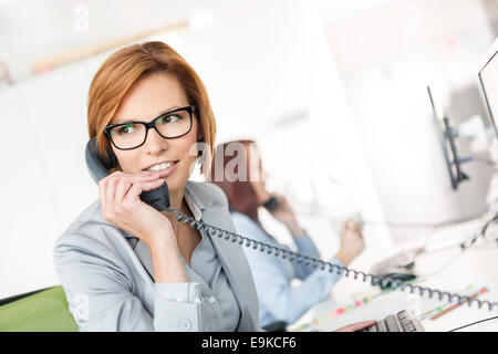 Young businesswoman talking on telephone at desk in office Banque D'Images