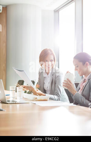 Les jeunes femmes d'avoir le déjeuner à table in office Banque D'Images