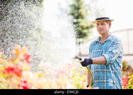 L'homme l'arrosage des plantes à l'extérieur de gaz à effet de Banque D'Images