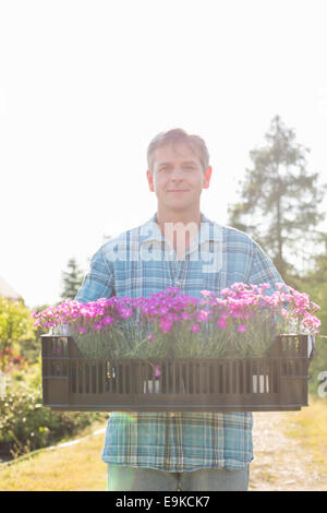 Portrait of man carrying crate avec pots de fleurs au jardin Banque D'Images